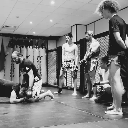 Entraînement technique de MMA au Luxembourg : un coach démontre une technique de grappling pendant un cours d'arts martiaux mixtes. Idéal pour améliorer ses compétences en combat.