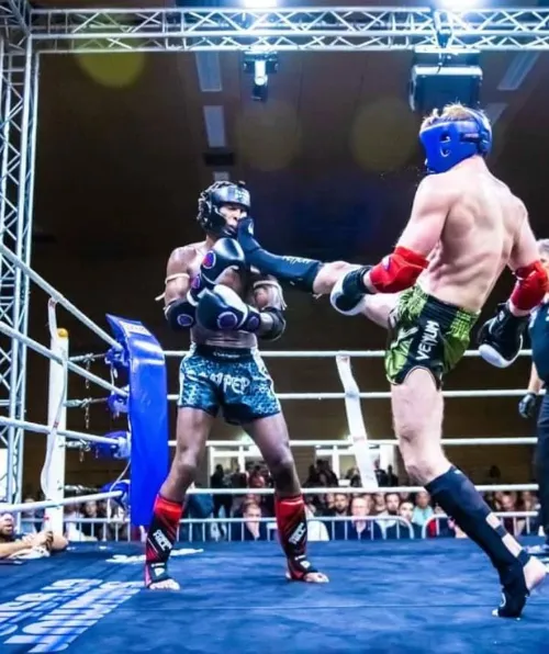 Un échange spectaculaire en pleine compétition de Muay Thai au Luxembourg. La maîtrise des coups de pied et la précision sont essentielles en boxe thaïlandaise pour dominer son adversaire sur le ring.